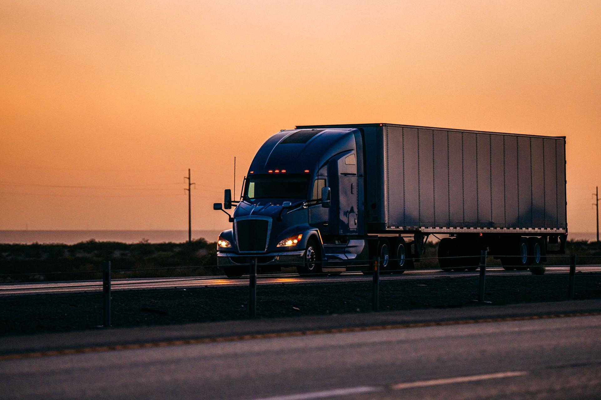 A Blue Semi Truck on the Highway in El Paso, Texas with a Vibrant Colored Orange Sunset